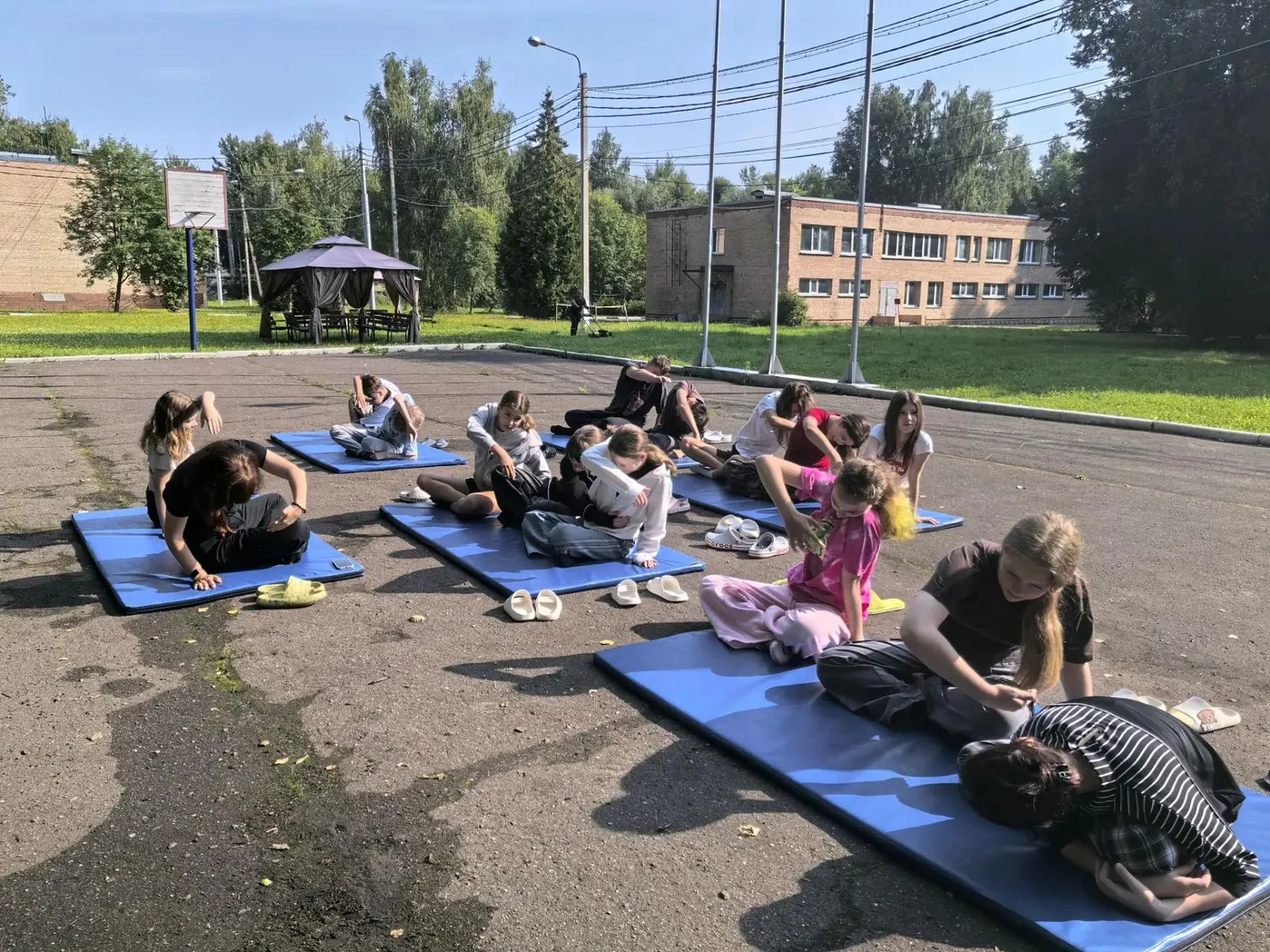 Дети выполняют упражнения на спортивных матах на свежем воздухе